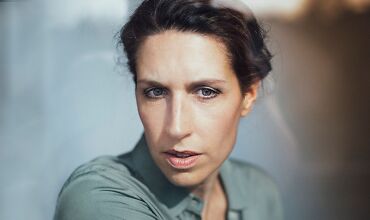 Auf dem Bild ist ein Abschnitt der Außenfassade des Aalener Rathauses zu sehen. Am Rathaus-Balkon ist ein Banner in den Farben der ukrainischen Nationalflagge angebracht. Der Brunnen, der vor dem Rathaus steht, ist ebenfalls zu sehen.