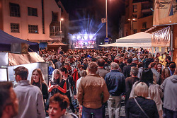 Auf dem Bild ist eine Menschenmenge auf dem Gmünder Torplatz bei Nacht zu sehen. Im Hintergrund tritt eine Band auf einer Bühne auf.