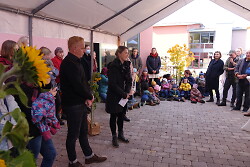 Auf dem Bild sind einige Erwachsene und Kinder bei der Eröffnung des Waldorf-Kindergartens im Hirschbach zu sehen.