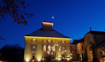 Auf dem Bild ist das beleuchtete Schloss Fachsenfeld in der Dunkelheit zu sehen.