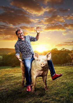 Auf dem Bild ist der Kabarettist Heinrich del Core zu sehen, wie er auf einem Schwein reitet.