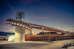 Auf dem Bild ist der Fußgängersteg über den Aalener Bahnhof in der abendlichen Dämmerung zu sehen.