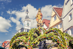 Auf dem Bild ist der Osterbrunnen mit dem Spion-Rathaus in Aalen zu sehen.