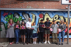 Auf dem Bild ist Oberbürgermeister Frederick Brütting mit einigen Jugendlichen vor einem Graffiti stehend zu sehen.