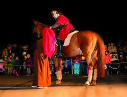 Auf dem Bild sind Kinder im Hintergrund zu sehen, die einer als St. Martin verkleideten Person auf einem Pferd zuschauen.
