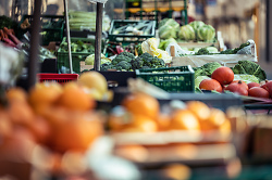Auf dem Bild sind verschiedene Obst- und Gemüsesorten, die an einem Marktstand verkauft werden, zu sehen.
