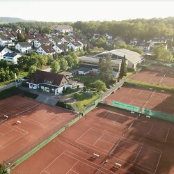 Das Bild zeigt eine Luftaufnahme von Tennisplätzen mit rotem Sand, dem Vereinsheim des TC Aalen sowie eine Tennishalle.