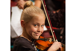 Auf dem Bild ist ein Mädchen zu sehen, das auf einer Geige musiziert.