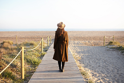 Auf dem Bild ist die Rückansicht einer Frau zu sehen, die auf einem Steg am Strand läuft.