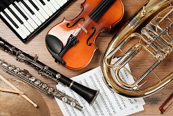Auf dem Bild ist eine Tuba, Querflöte, Geige, Klarinette sowie ein Keyboard und ein Notenblatt zu sehen.