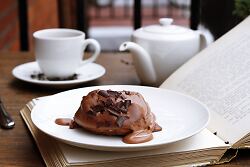 Holztisch Schokoladen-Süßigkeit auf einem Teller, der auf einem geöffnetem Buch steht